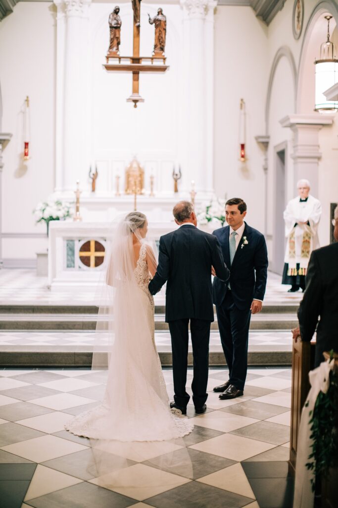 Bride's father walking her down the aisle during church ceremony 