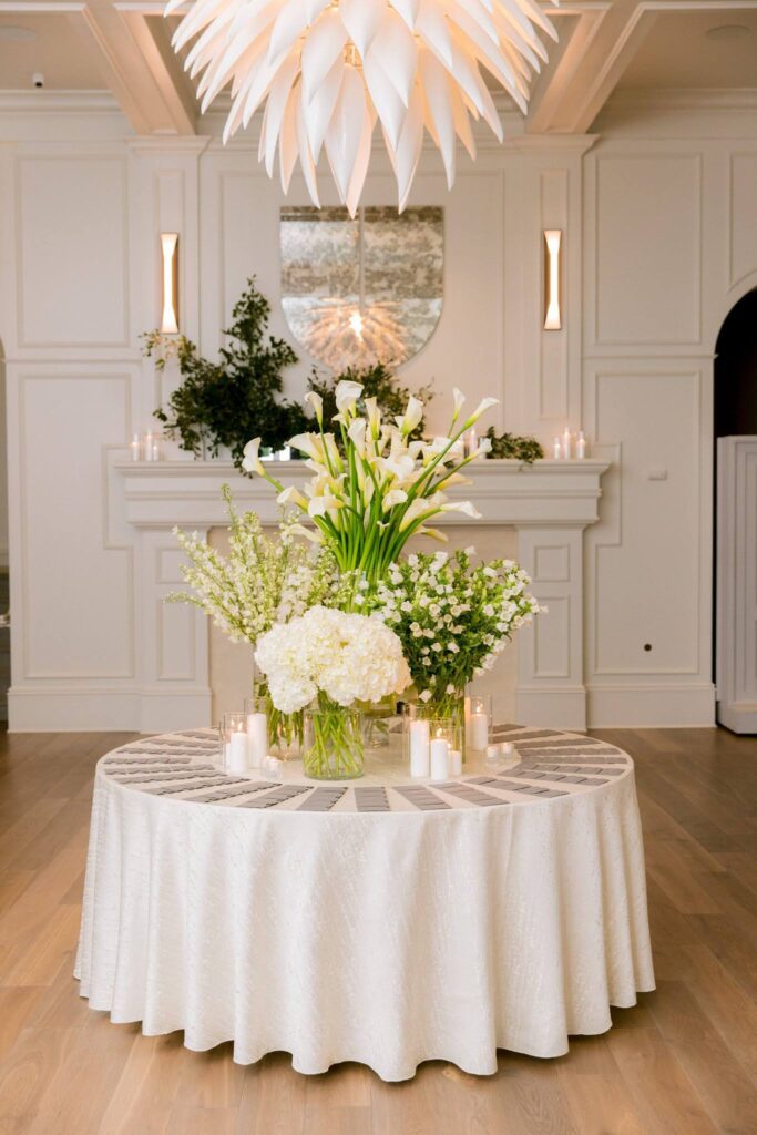Escort card table arrangement will gorgeous white florals 